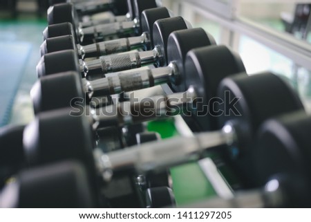 Row of dumbbells in gym. Black dumbbell set in sport fitness club center.