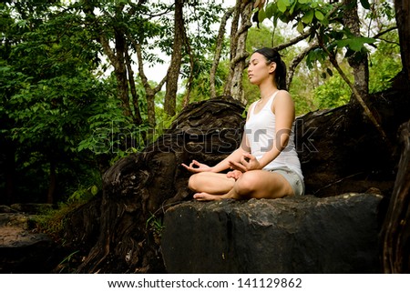 Woman training yoga and meditation on the rock at the mountain