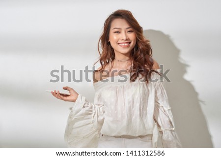 pretty asian woman in casual wear holding smartphone in one hand, dancing