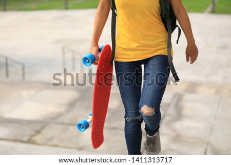 Woman skateboarder walking with skateboard in hand at city stairs