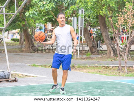 Basketball in hand Asian man to exercise Background  tree at Bang Yai Park , Nonthaburi in Thailand.