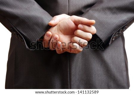 hands held behind the back of a suited man Royalty-Free Stock Photo #141132589
