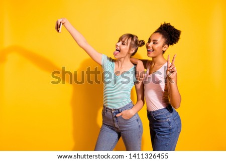 Portrait cheerful excited fun students beautiful make photo v-sign tongue-out grimace free time weekend holiday summer travel wavy bun top-knot trendy stylish jeans t-shirt isolated yellow background