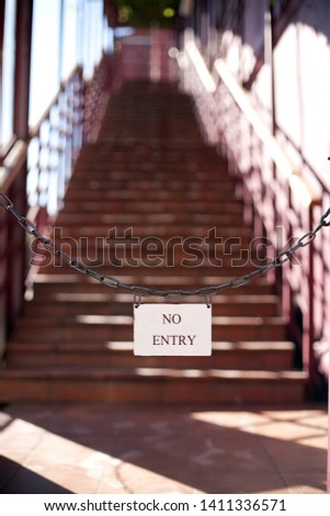 the plate of an entrance is not present on a chain against the background of a metal ladder of red color