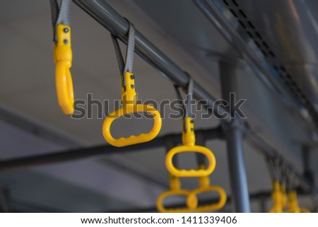 yellow plastic hanging handles on the belts hang under the ceiling of the passenger bus Royalty-Free Stock Photo #1411339406