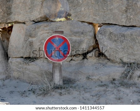 No stopping prohibitory road sign.
Dirty prohibitory road sign near the stone wall.