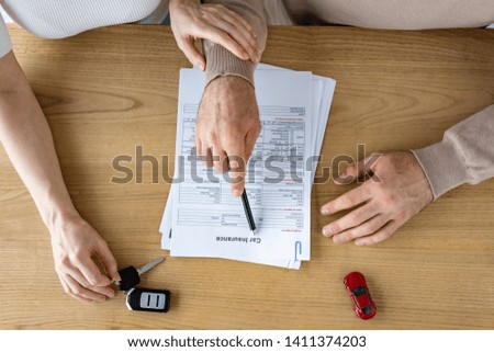 top view view of man holding pen near document with car insurance lettering and woman 