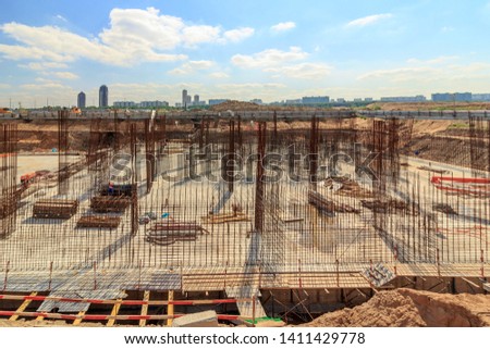 Reinforcement of pylons and walls of underground parking. Construction process in pit building under construction. Beginning of reinforcement of foundation slab under section of high-rise building.