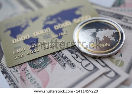 Silver coin ripple XRP closeup lie on table with dollar paper and credit card aganist table background. Cryptocurrency exchange concept.