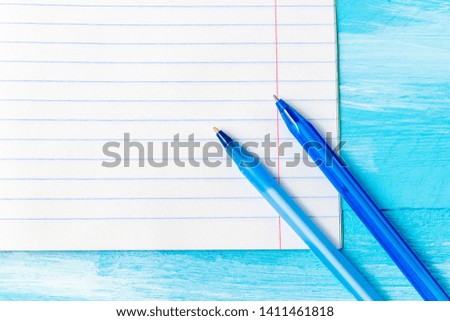 Notebook blank page with colorful pencil, marker and pen composition mock-up Back to school concept with stationery office supplies on a blue wooden background with copy space close-up top 