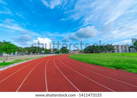 The outdoor track and field track is under the blue sky and white clouds.