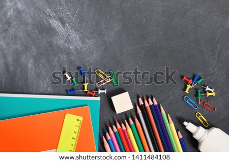 Bright stationery on a black Board background notebooks, pencils, scissors and others. Concept back to school