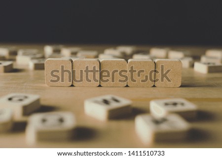 selective focus of five blank cubes surrounded by blocks with letters on wooden surface isolated on black