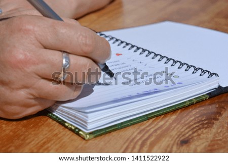 Woman writing in a bullet journal, selective focus on pen nib