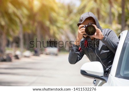 A man photographer takes images with dslr camera outside car. Professional journalist taking photos outdoors. 