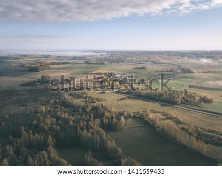 drone image. aerial view of rural area with fields and forests covered in autumn mist. latvia - vintage old film look