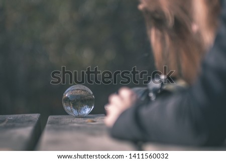 lensball in autumn reflecting nature around it. fall colors hold in human hand - vintage old film look