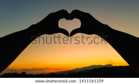 The girl's shadow showing the heart-shaped symbol of love, friendship and compassion on the sky's background in the evening to show her lover the love she had for Valentine's Day.
Love concept