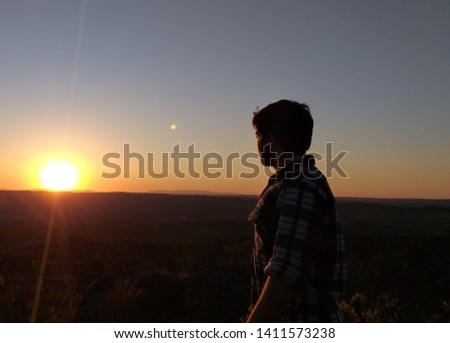 man looking at the sunset on top of a mountain