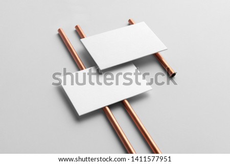 Real photo, business cards branding mockup template to place your design, isolated on light grey background, with copper tubes.