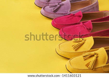 Colorful woman mocassins on bright yellow background, with copy space