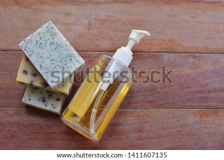 Three kinds of homemade of soap bar with texture of poppy seed scrub and liquid soap in refill plastic bottle lay down on old wooden plank, top view still life with space, natural beauty products 
