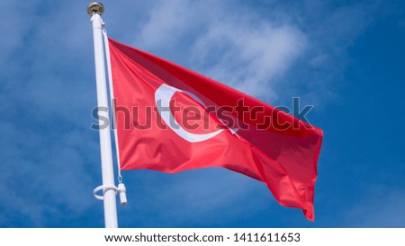 Turkish flag waving in sunny blue sky.