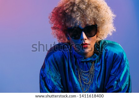 Young black woman with sunglasses in studio setting looking at the camera Royalty-Free Stock Photo #1411618400