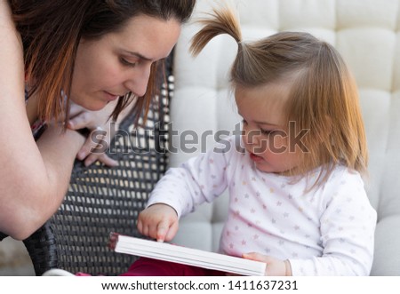 Mom and daughter reading a book on the terrace. Awesome family moments. Outdoor photography