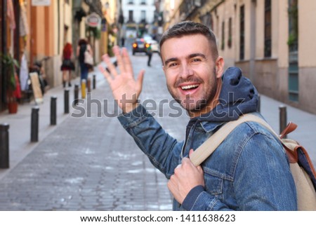 Man saluting someone he knows outdoors