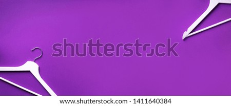 White clothes hangers on violet background with copy space. Flat lay. Top view. Minimalism style. Creative layout. Fashion, store sale, shopping concept. Banner for feminine blog.