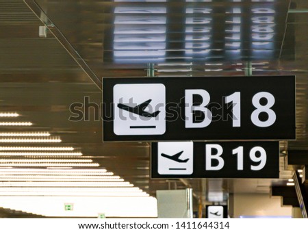 Information panel with the pictogram of an airplane taking off to indicate the boarding gate B 18 inside an airport. Concept of travel and mode of transport