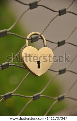 A heart-shaped lock hung on a fence Royalty-Free Stock Photo #1411737347
