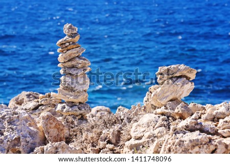 Zen pyramid of stacked rough stones on the blurred sea background. Concept of balance and harmony, nobody, copy space