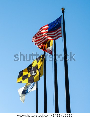 American Flag, Maryland State Flag and City of Baltimore Flag Waving on a Clear Day with Blue Sky Background