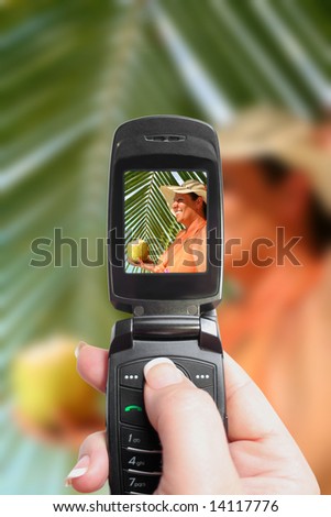 taking a mobile picture of voluptuous woman holding coconut with palm backdrop on a tropical beach