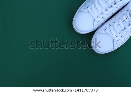 white leather sneakers on a leather green background, a place for an inscription on the background near the sneakers