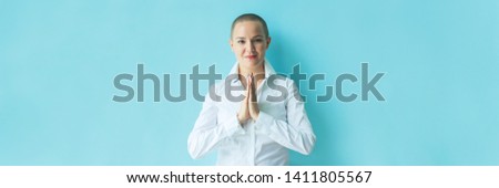 Greeting with thai gesture wai. Sign language. Portrait confident beautiful happy young bald woman in white shirt on colored background wall. Human emotions facial expression. Banner