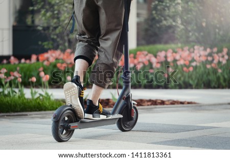 Close up of man riding black electric kick scooter at beautiful park landscape Royalty-Free Stock Photo #1411813361
