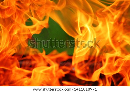 Close-up charcoal grill with orange powerful flame on green background