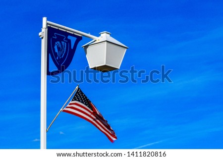 Street white lantern light with blue  Native American  Sign and American Flag in a blue sky background during day time at Winnemucca, Nevada, USA