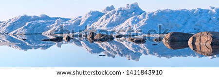 Panorama of ice hummocks and boulders reflected in the lake surface. 