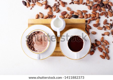Homemade hot chocolate drink decorated with chocolate, cocoa and cocoa beans over a white texture background. Top view, flat lay. Copy space
