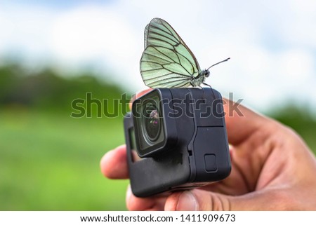 Black 4K action camera, with butterfly.