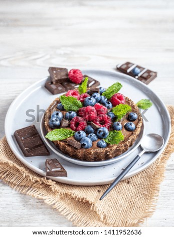 Raw Gluten free home made chocolate tart with fresh berries and peppermint leaves