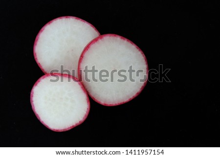 Food photo with sliced ​​and halved radishes on a black dark background. Top view