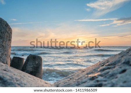  View from the breakwater at sunset over the Baltic Sea. Beautiful waves, the sky at sunset.