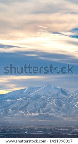 Vertical Striking sunlit mountain coated with snow under a vivid blue sky with clouds