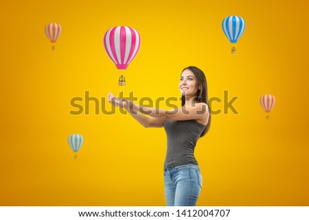 Young smiling brunette girl wearing casual jeans and t-shirt with palms up and pink hearts on yellow background. People and objects. Feelings and emotions. Gestures and body language