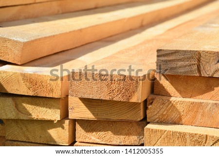 Stacked lumber. Folded wood.Closeup wooden boards.The surface of the end of the board.Lots of planks stacked on top of each other in the warehouse.Lumber for use in construction. Royalty-Free Stock Photo #1412005355